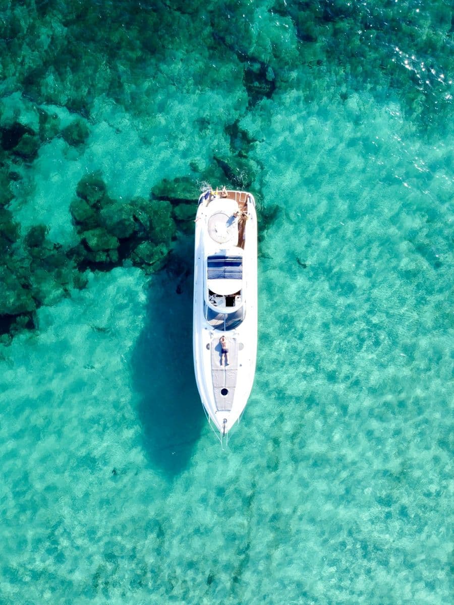 A white yacht on turquoise water, seen from above